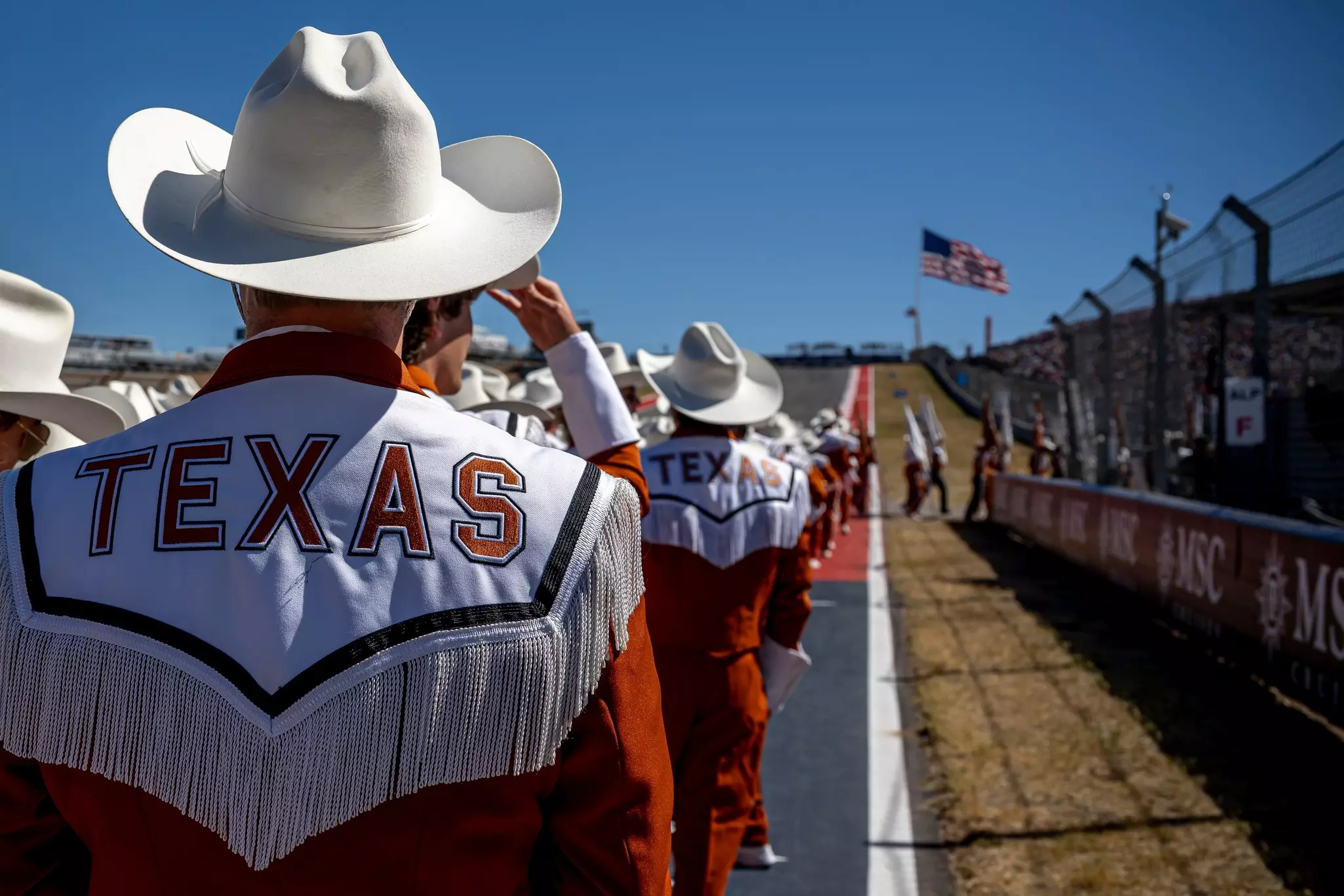 People wearing cowboy hats are seen from behind on a race track