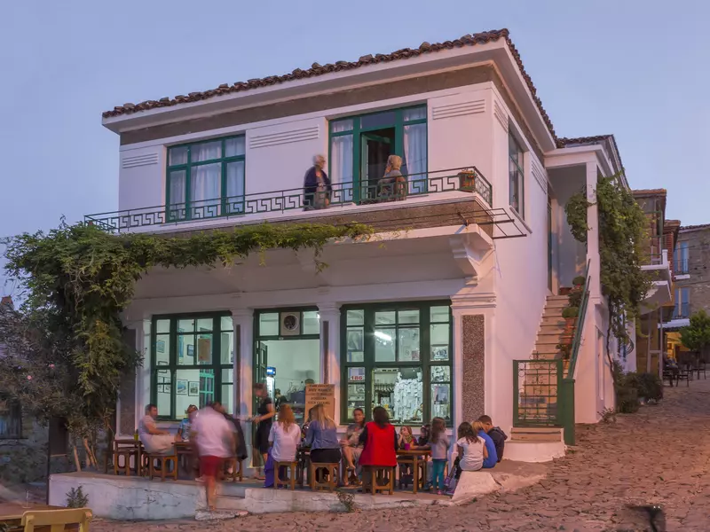 People gather outside a busy bar at dusk.