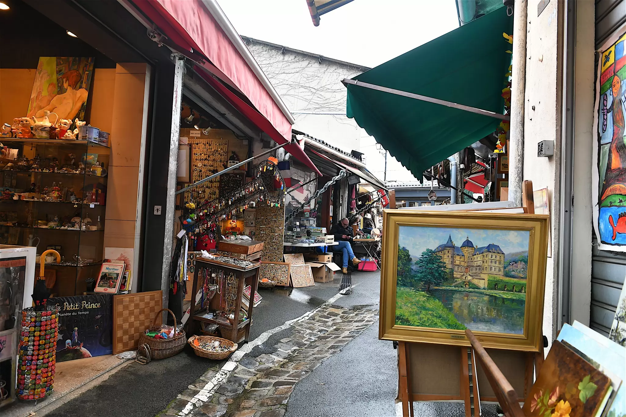 An alleyway in a market lined with stalls selling paintings, keyrings, posters, jewelry and bric-a-brac in Paris in winter