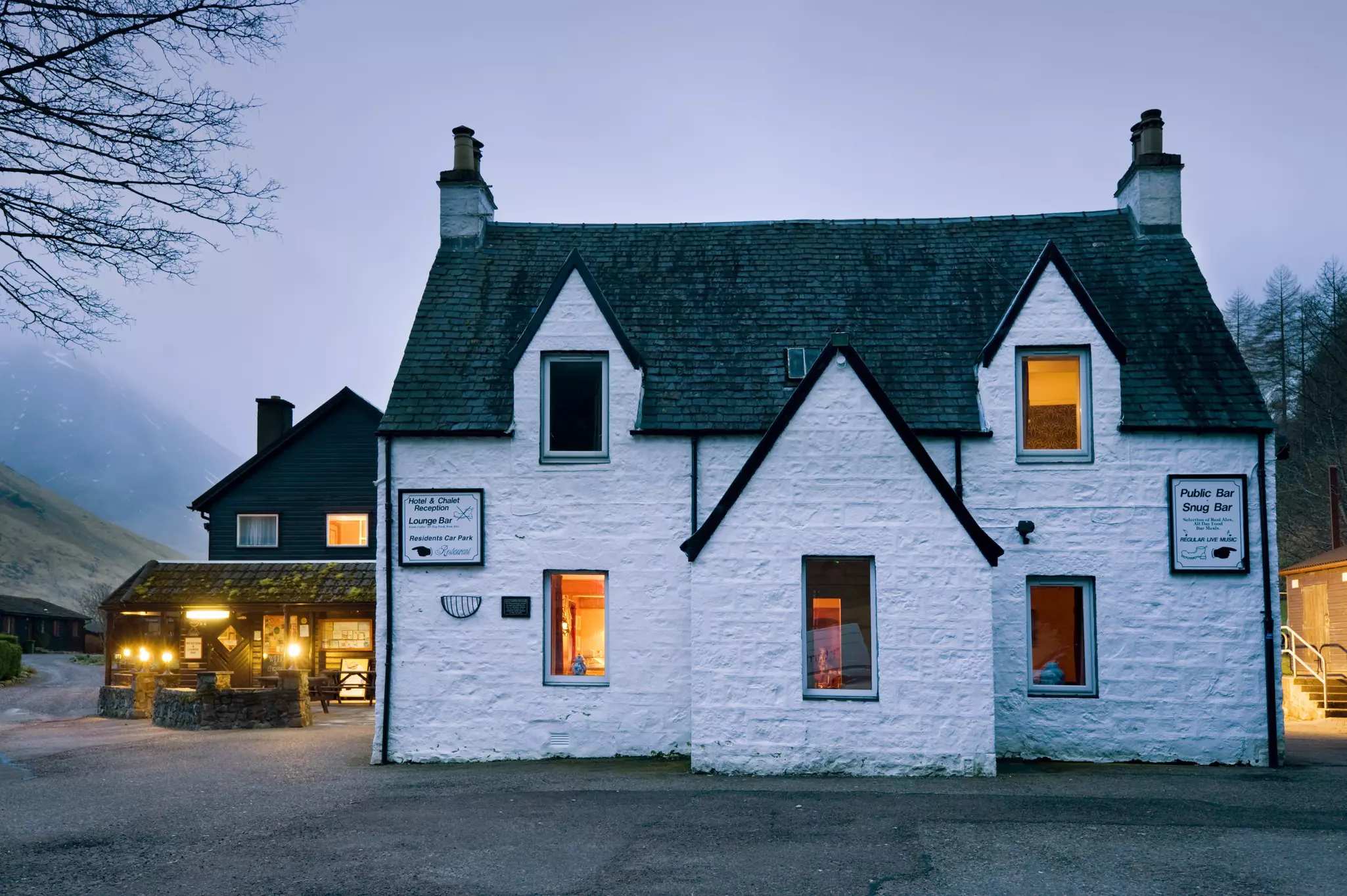 A historic white-painted pub in the countryside is pictured at dusk.