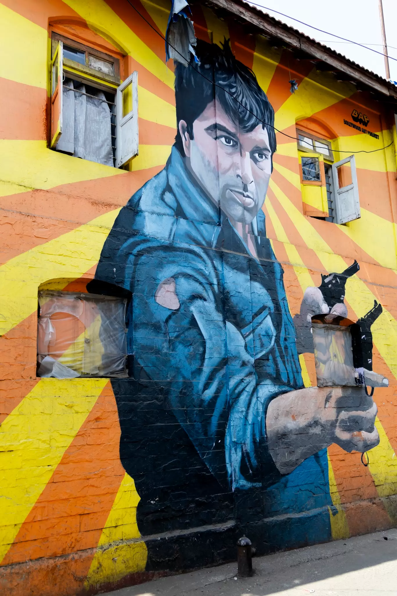 Wall painted with a large mural of a male film star, the street art is by the Bollywood Art Project.