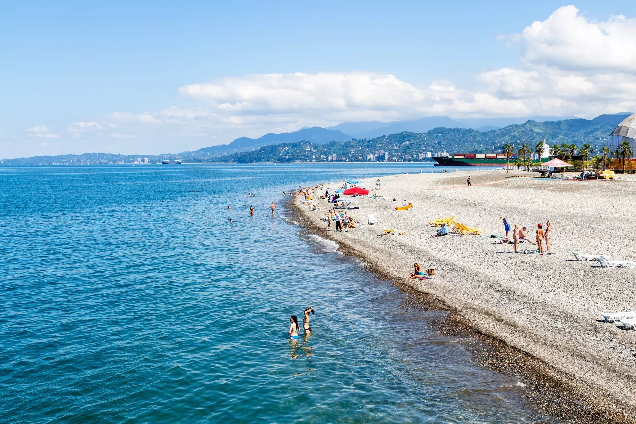 People relaxing on a pebble beach on a sunny day.