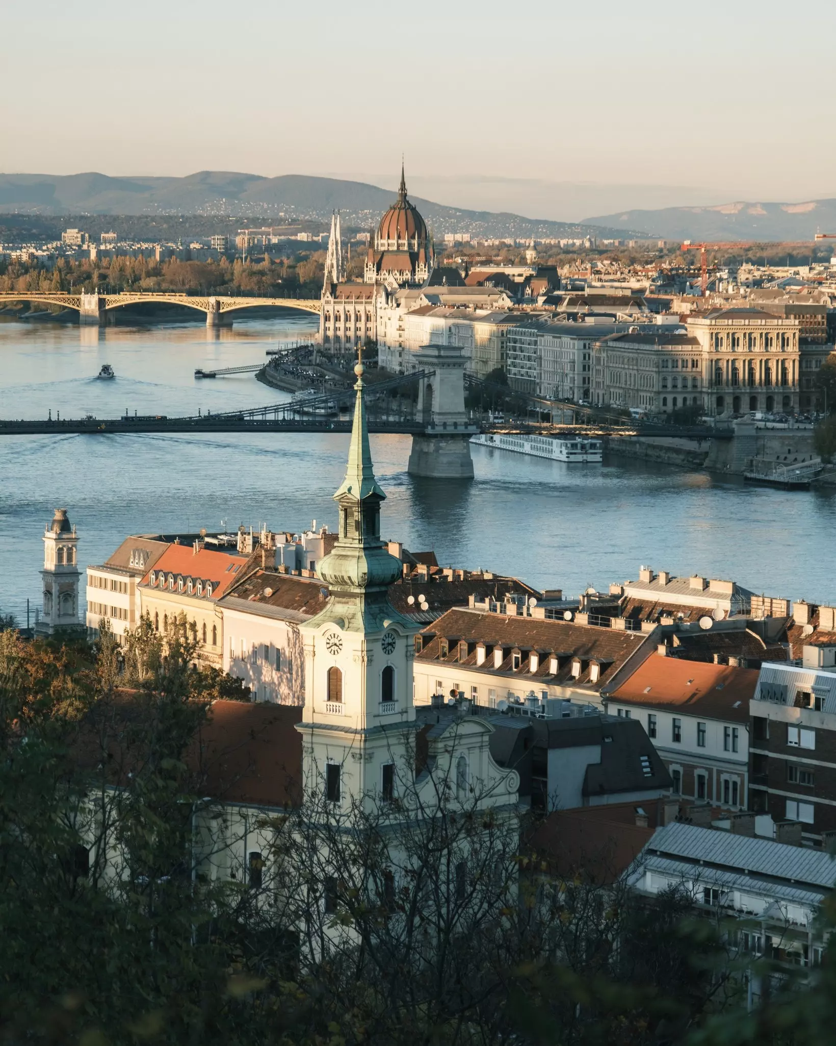Spires and historic buildings on either side of a river crossed by bridges.