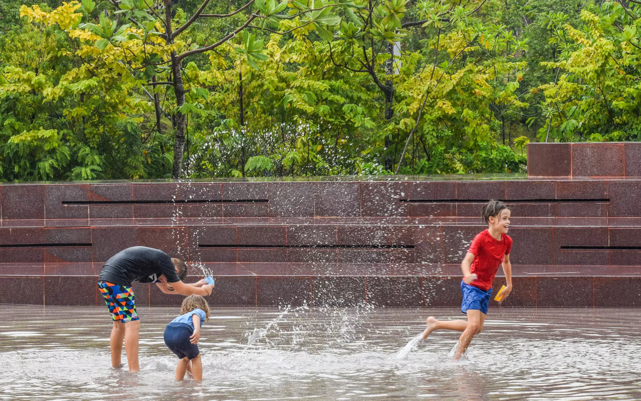 Children play in a water feature at an urban park.