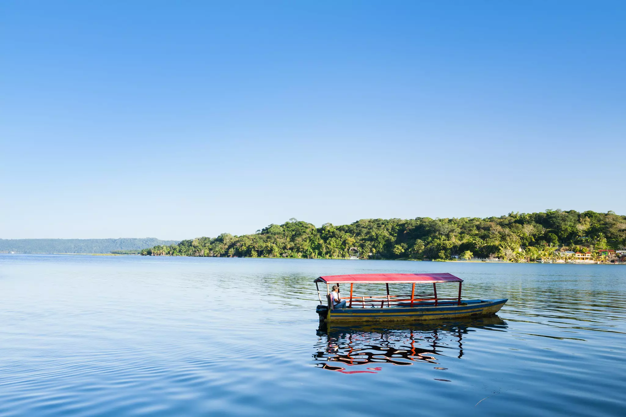 A small boat in a lake surrounded by jungle