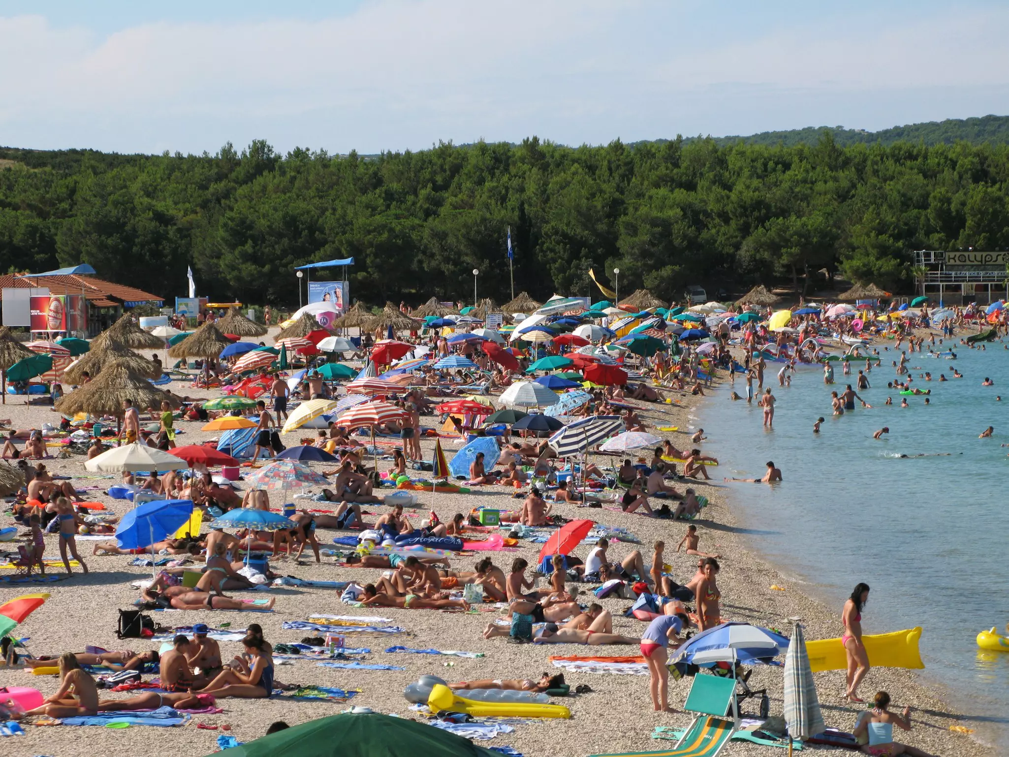 Crowds sunbathing and swimming on Zrče beach during summer