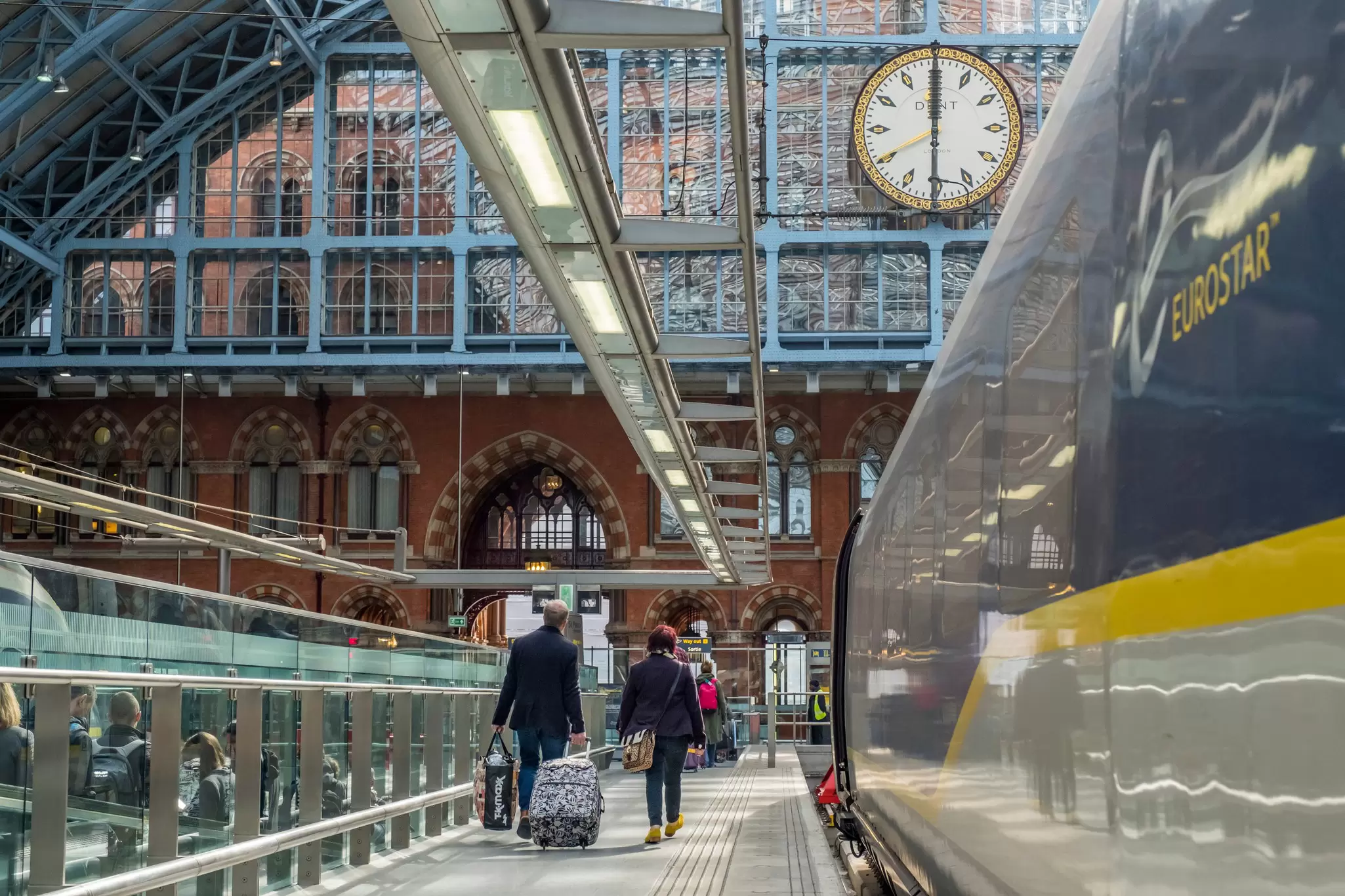 The Eurostar train arrives at London's St Pancras International station, as passengers walk down the platform with their bags.