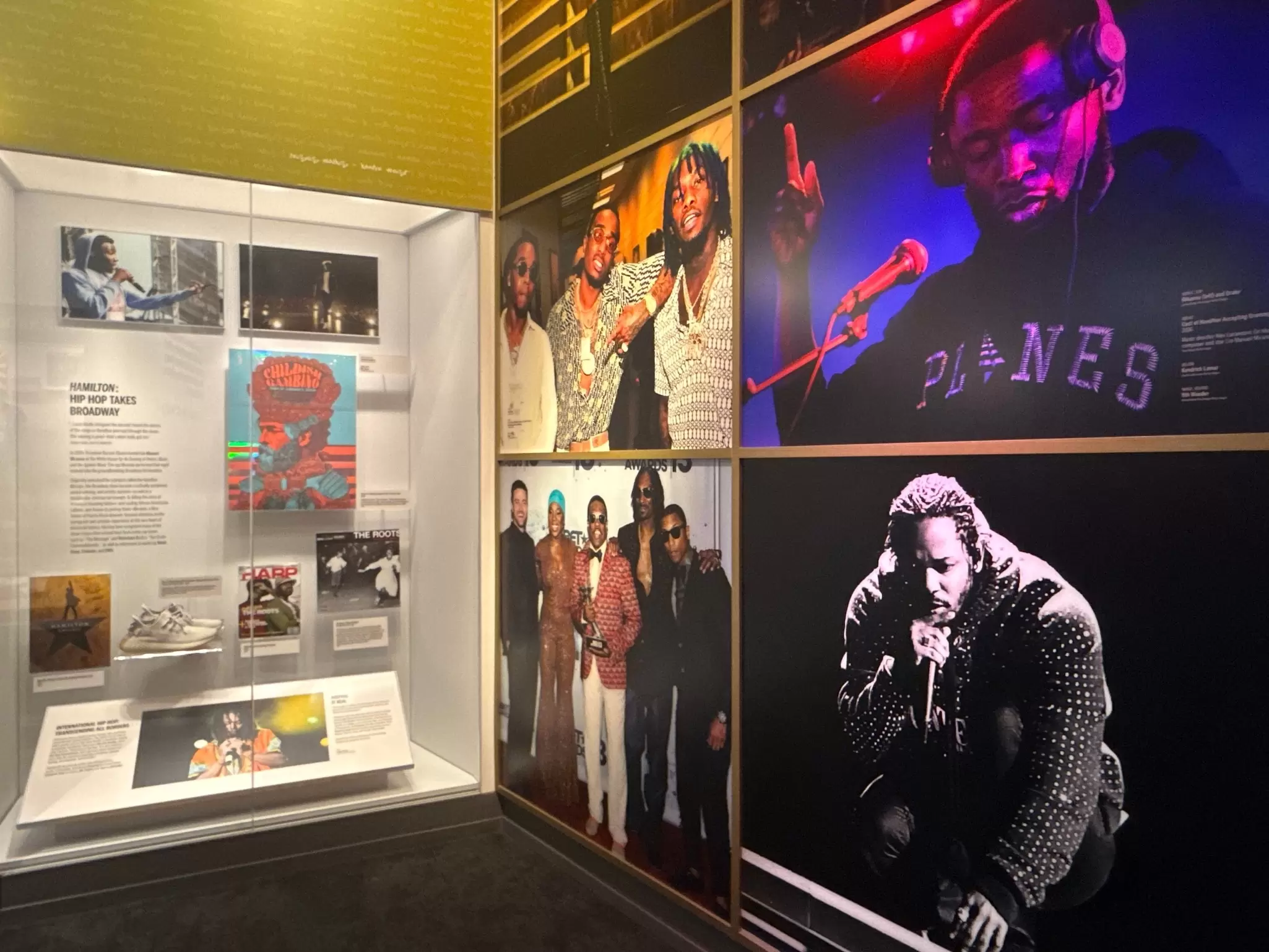 Museum exhibit wall with large photos of musicians and a display case of memorabilia at a Nashville music museum.