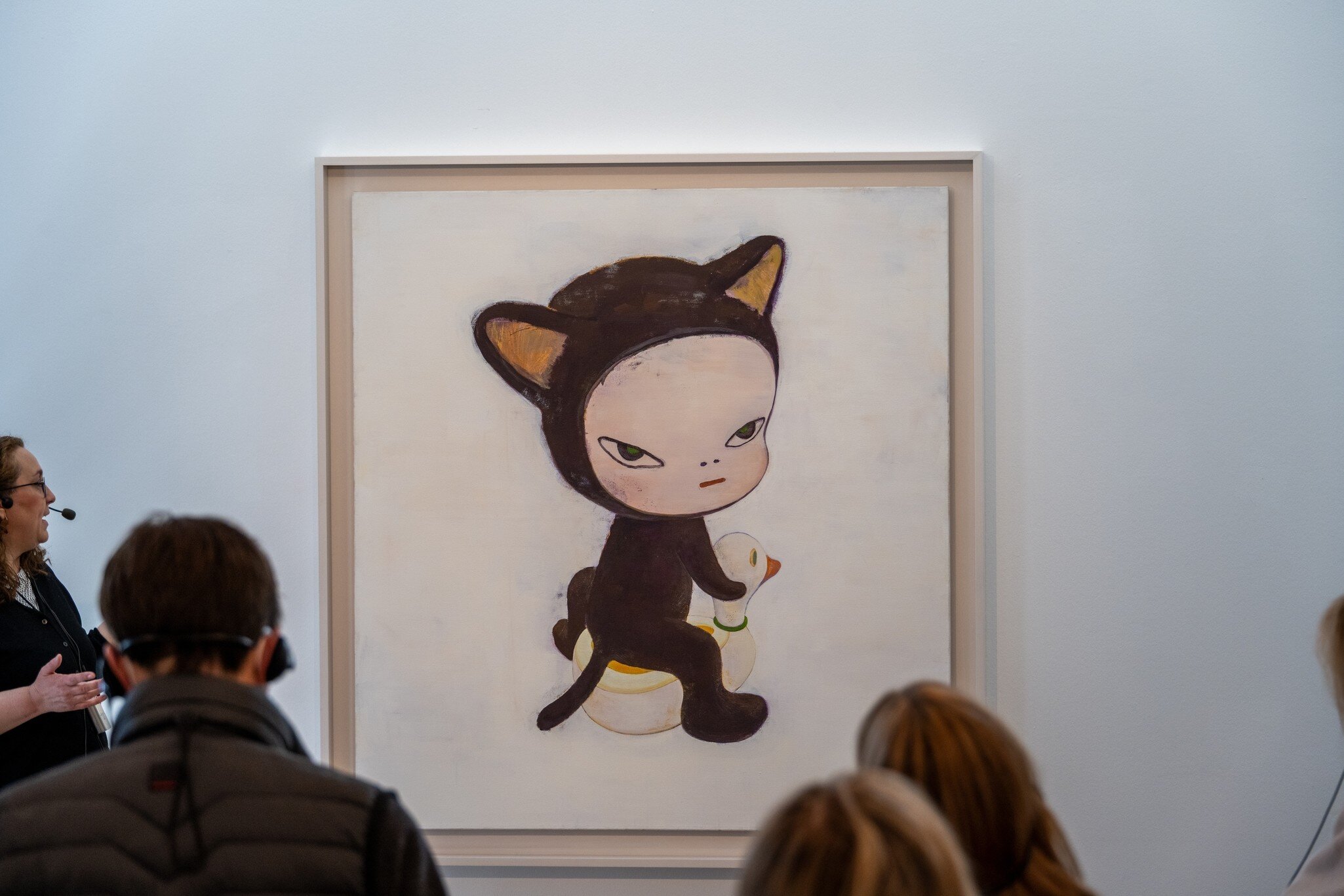 Museum gallery scene with visitors viewing a large painting of a cat-suited child sitting on a duck float, at Museum Frieder Burda in Baden-Baden, Germany.