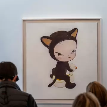 Museum gallery scene with visitors viewing a large painting of a cat-suited child sitting on a duck float, at Museum Frieder Burda in Baden-Baden, Germany.
