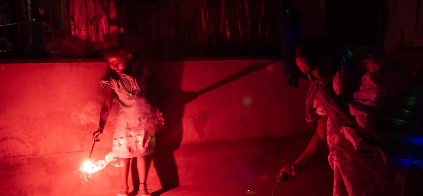 A child and her grandmother lighting firecrackers at night