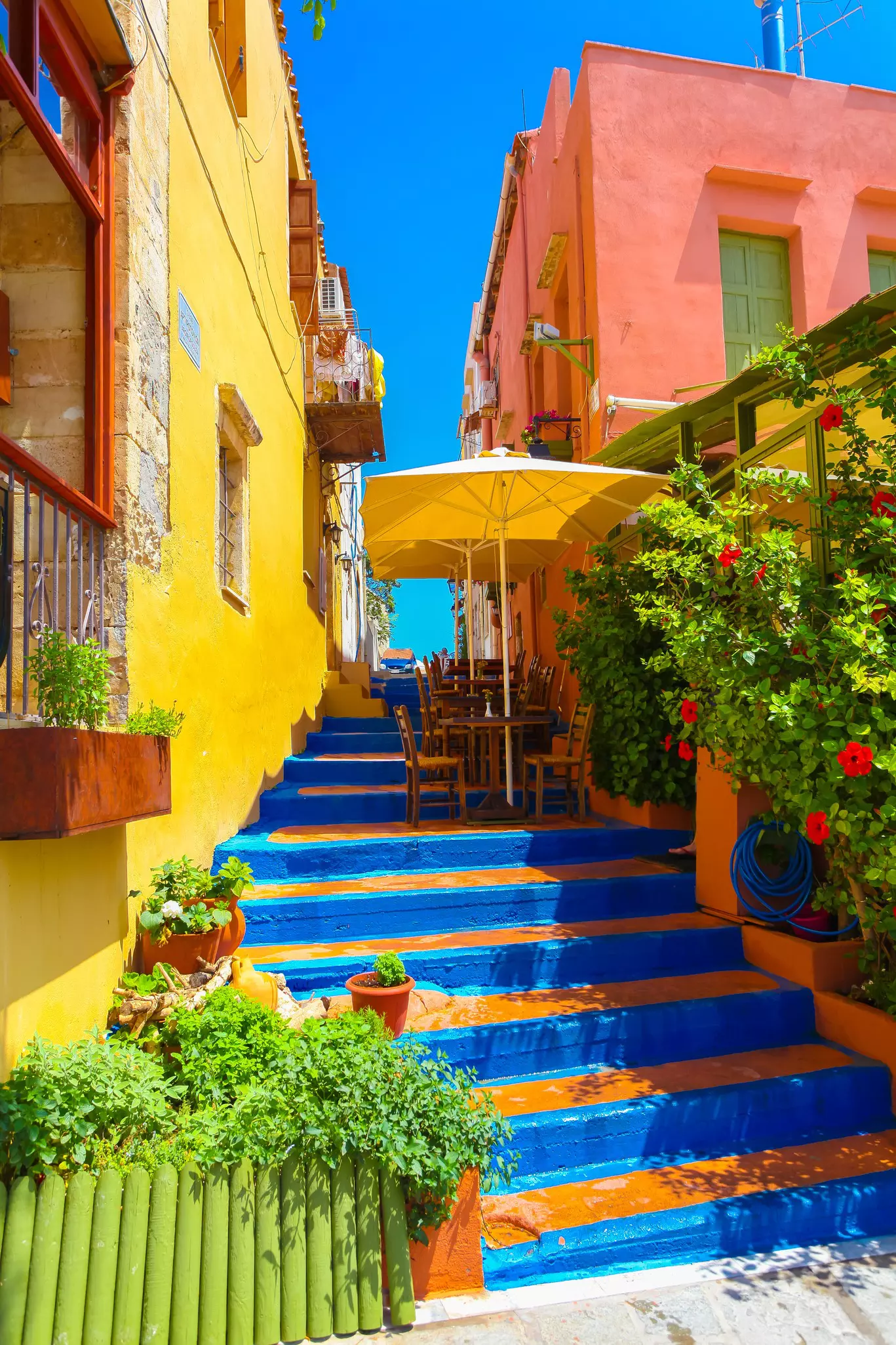 Colorful steps between houses lead up to an open air cafe and blue sky