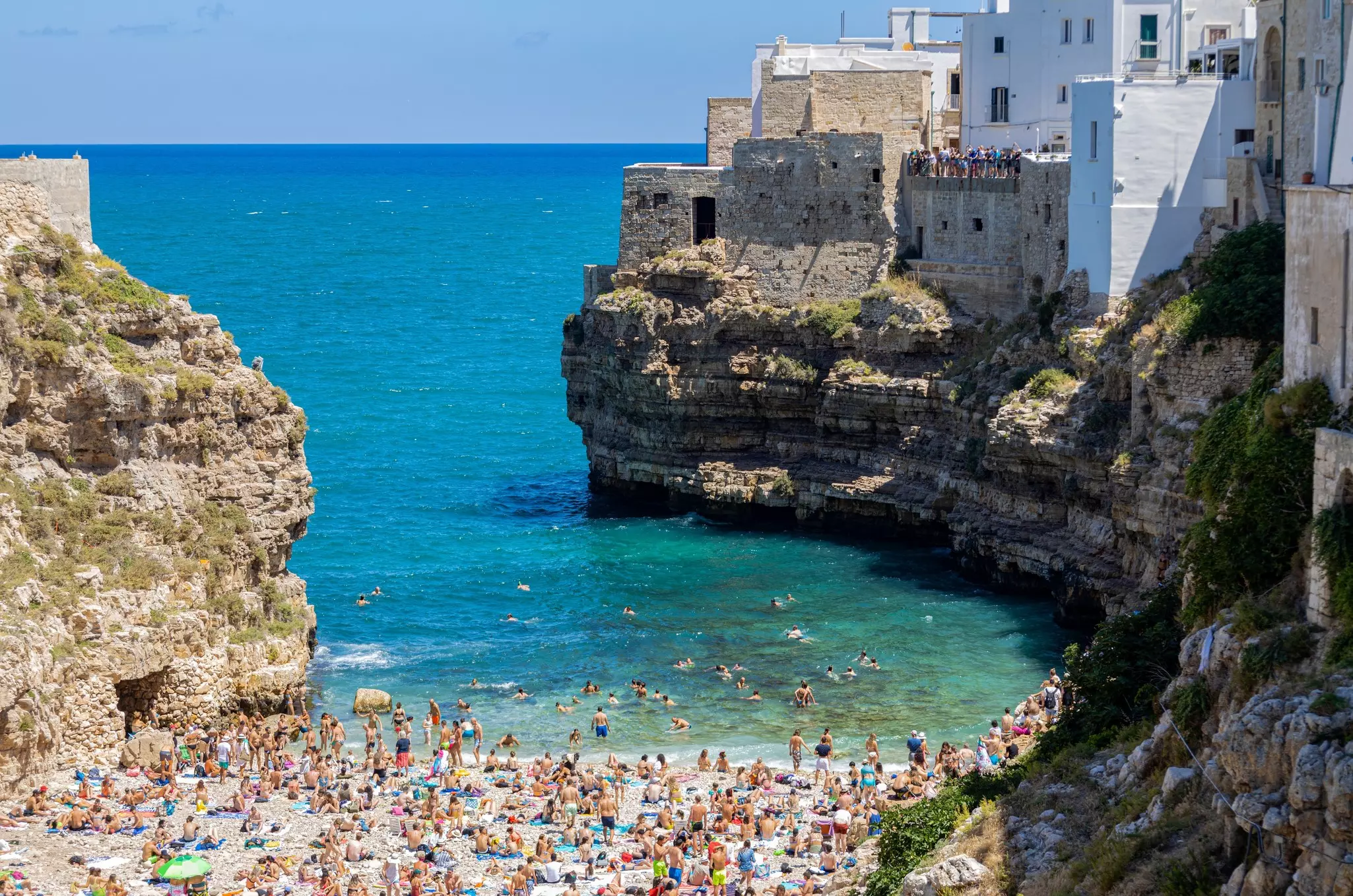 People in the water and on the sand at Polignano a Mare beach