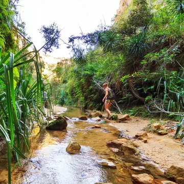 Woman hiking across a small stream in Isalo National Park.