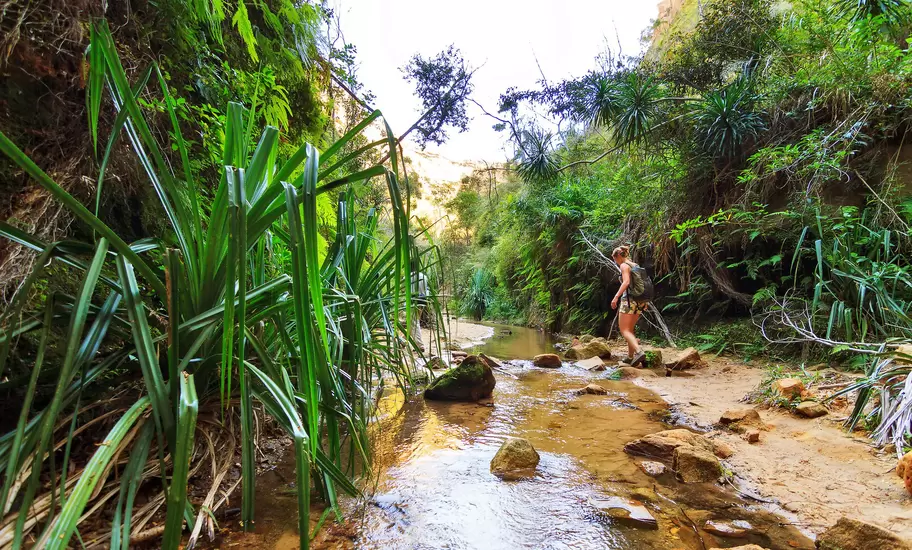 Woman hiking across a small stream in Isalo National Park.