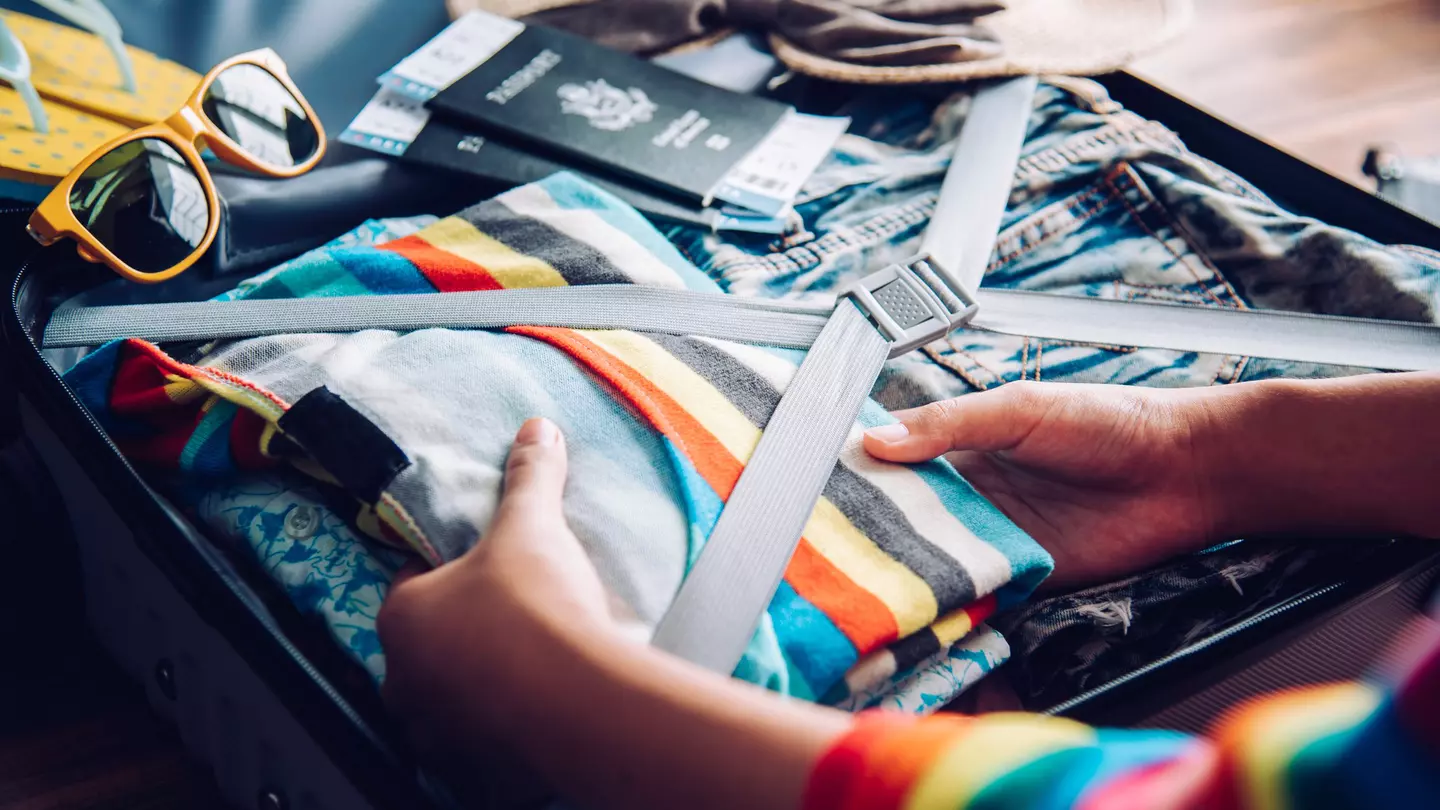 Hands of a woman packing her suitcase at home.