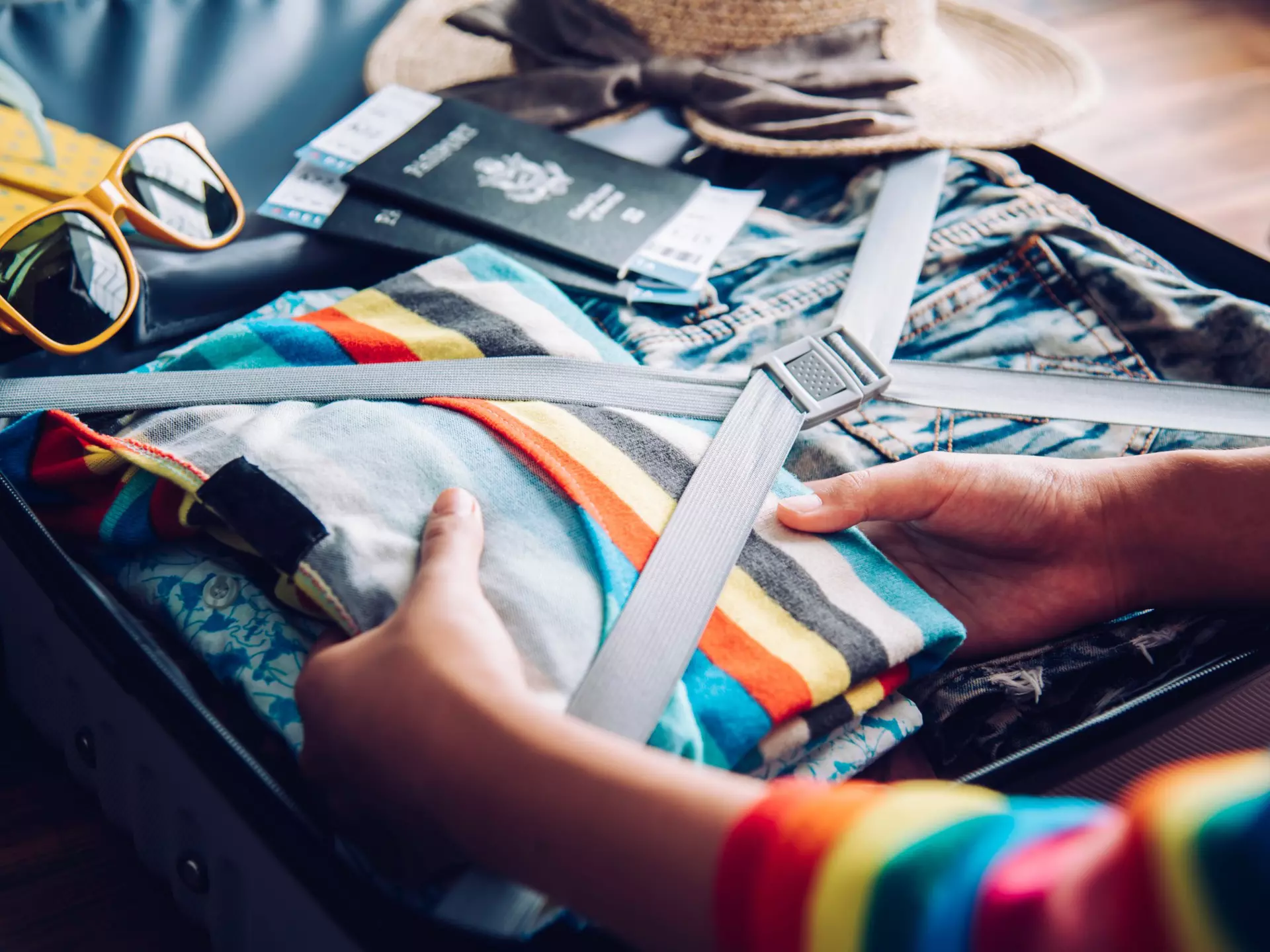 Hands of a woman packing her suitcase at home.