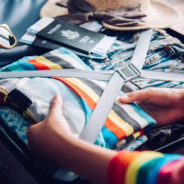 Hands of a woman packing her suitcase at home.