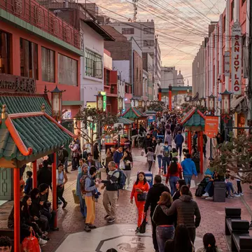 People walk down a pedestrianized street in a city at dusk.