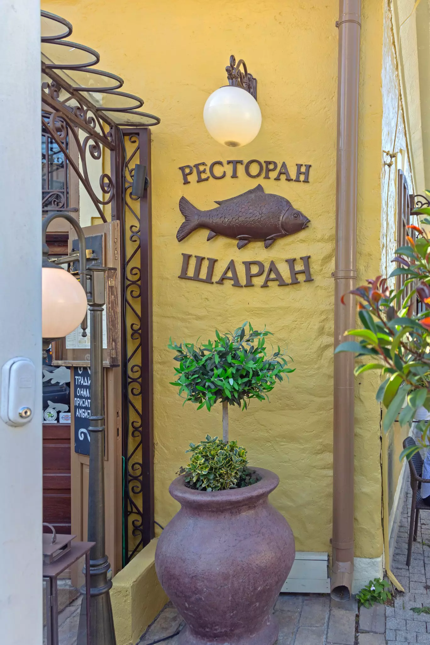 A large brass fish fixed to the exterior wall of a restaurant marking the entrance.