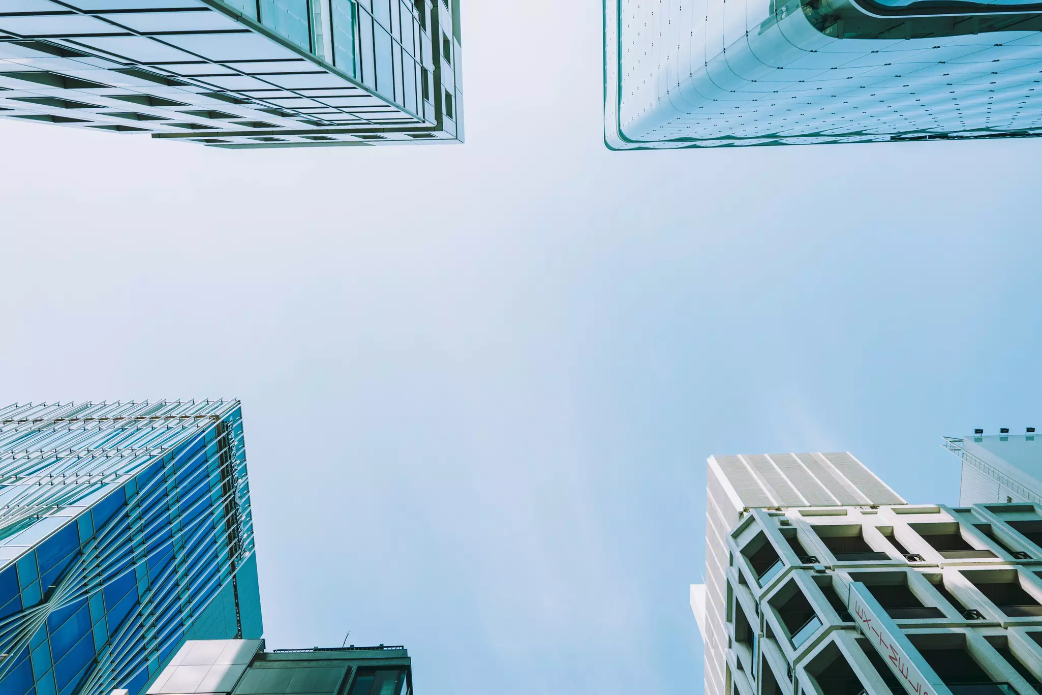 Looking up at tall buildings in Ginza district, Tokyo with blue sky beyond. 