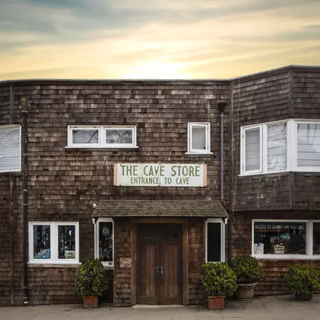 A shingled storefront with a sign above the door for The Cave Store.