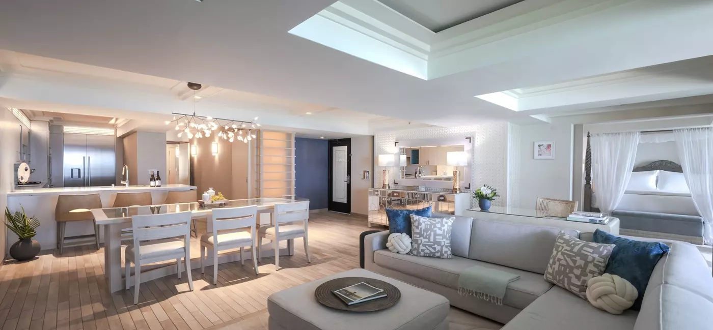 A vast hotel suite with couch, dining table and kitchen area