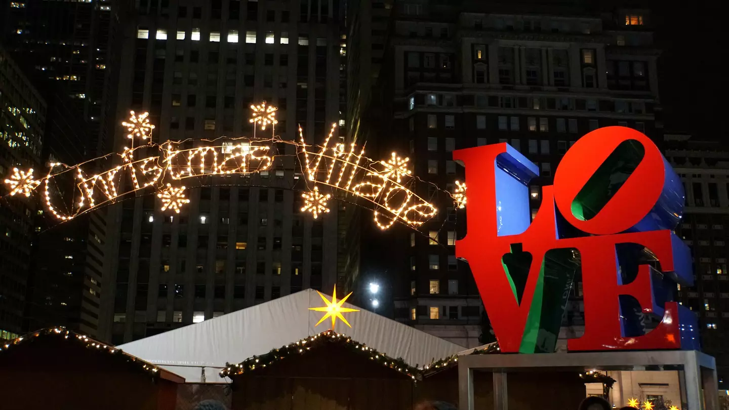 A large lit-up sign that reads "Christmas Village" next to a red sculpture spelling out the word "LOVE"