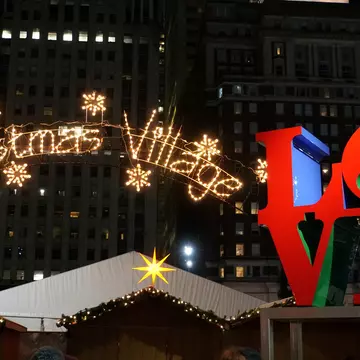 A large lit-up sign that reads "Christmas Village" next to a red sculpture spelling out the word "LOVE"