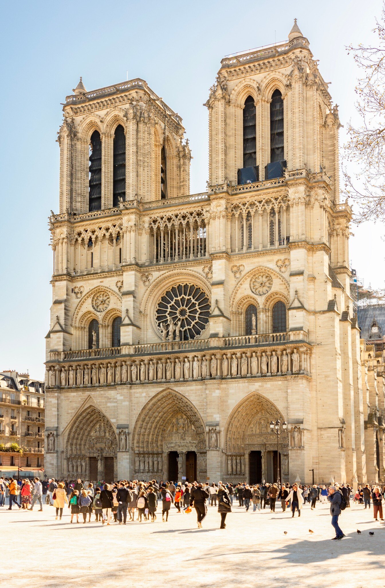 Crowds walking in front of the iconic Notre-Dame de Paris Cathedral.