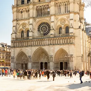 Crowds walking in front of the iconic Notre-Dame de Paris Cathedral.