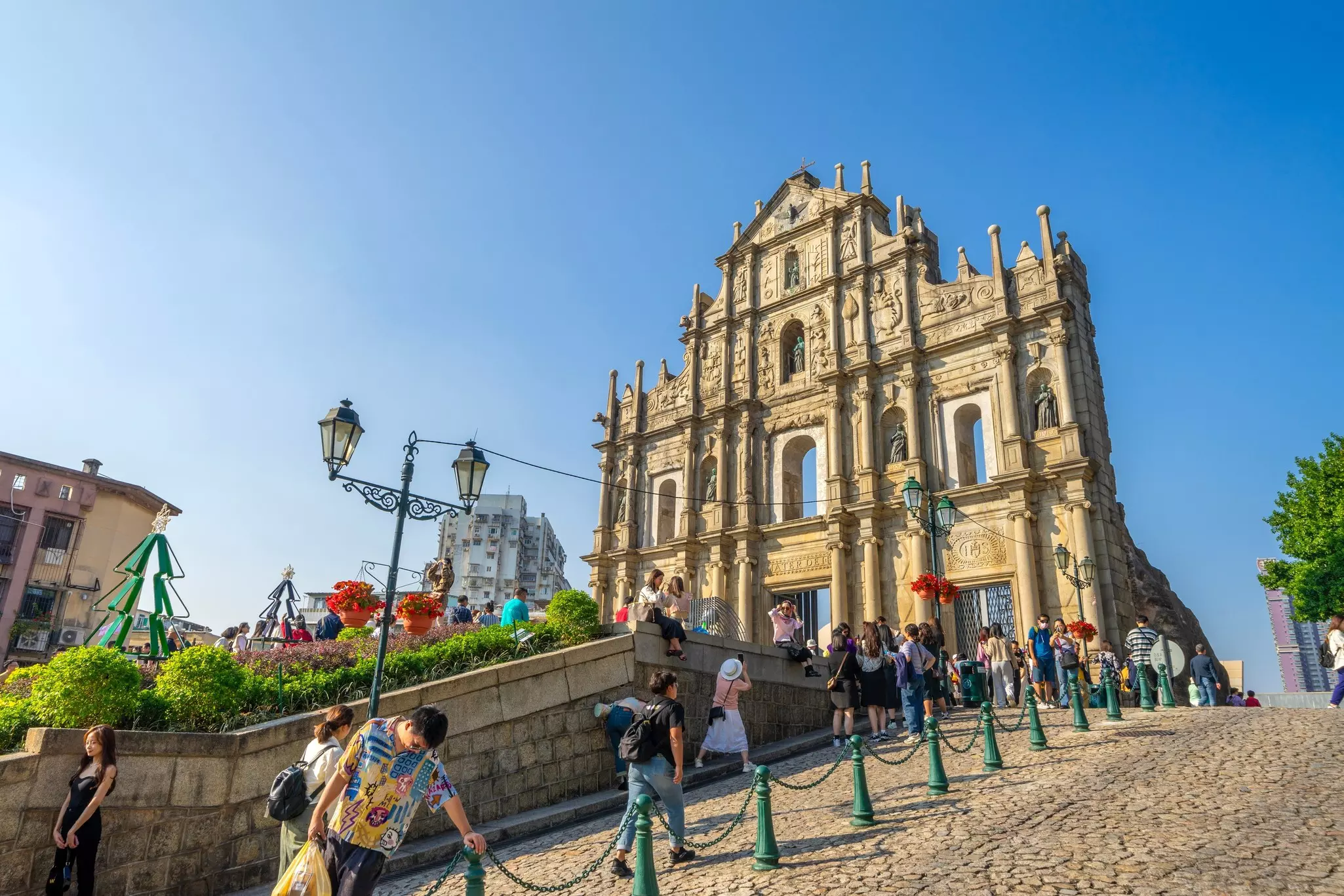 People visiting the ruins of the Church of St Paul with a blue sky above