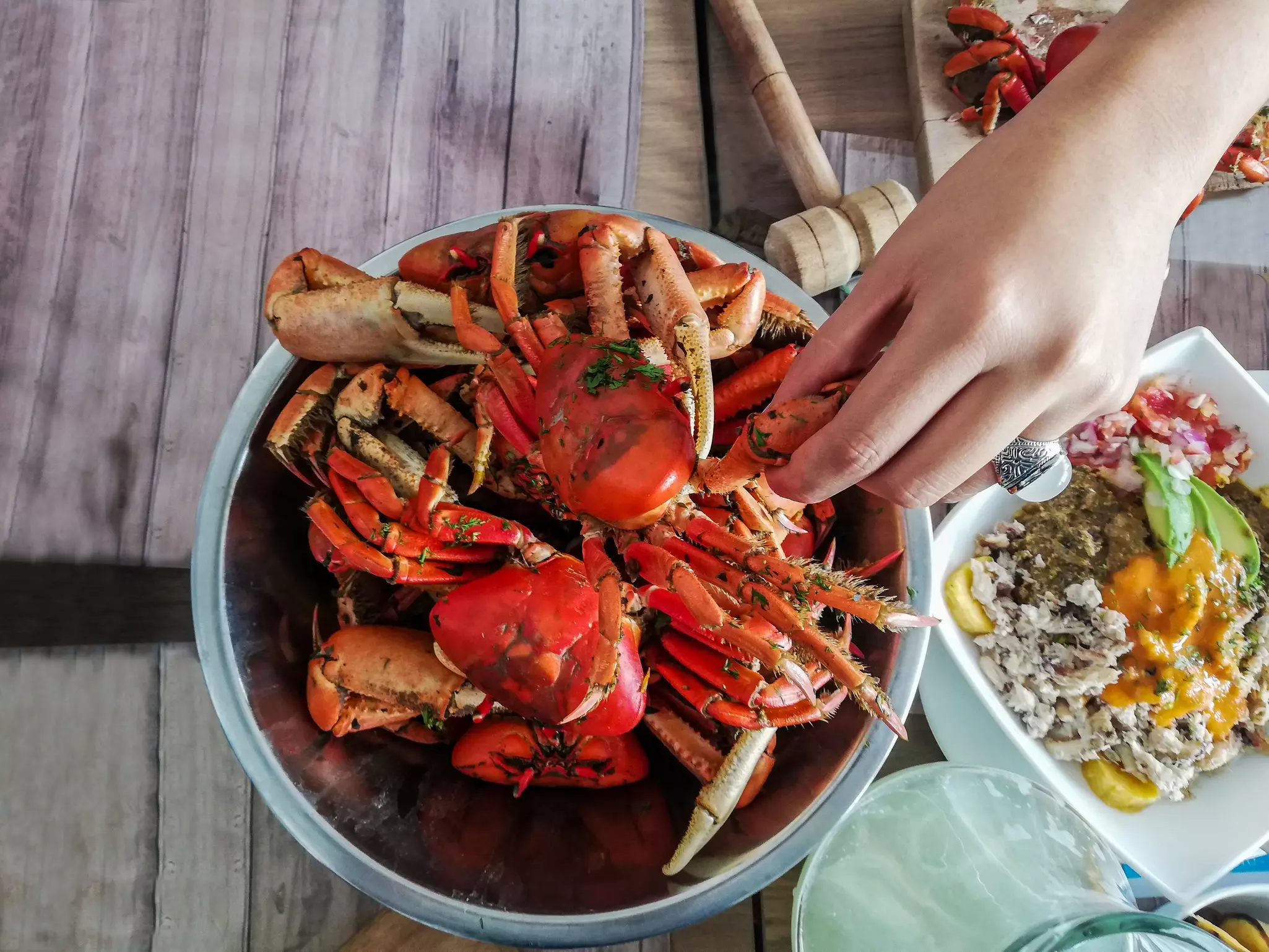 Aerial shot of a plate of crabs served in a bowl with one hand that will take a fat leg.
