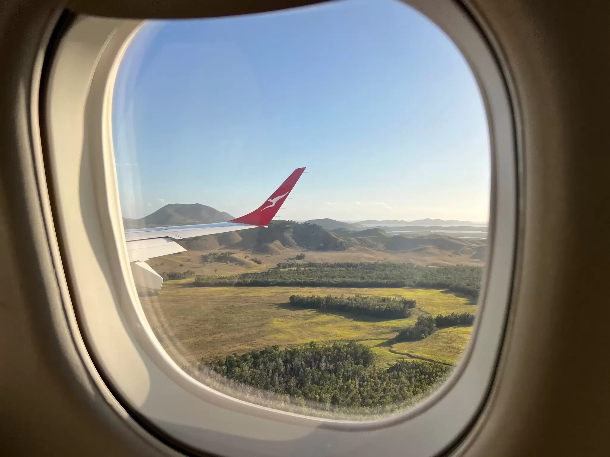 A green field through an airplane window.