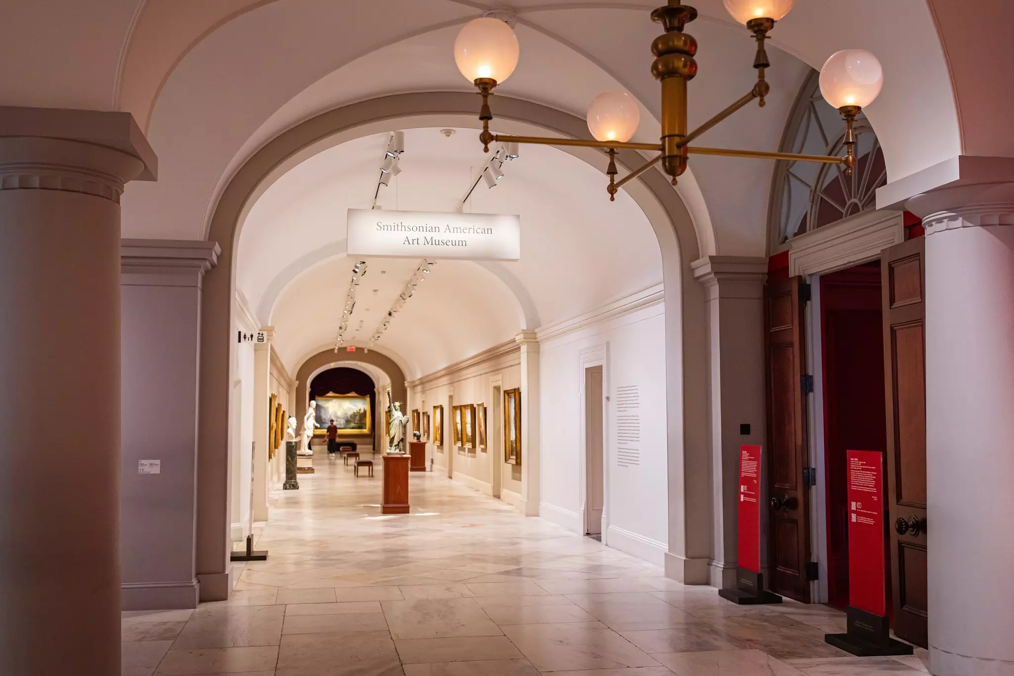 The inside of a museum with archways and sculptures.