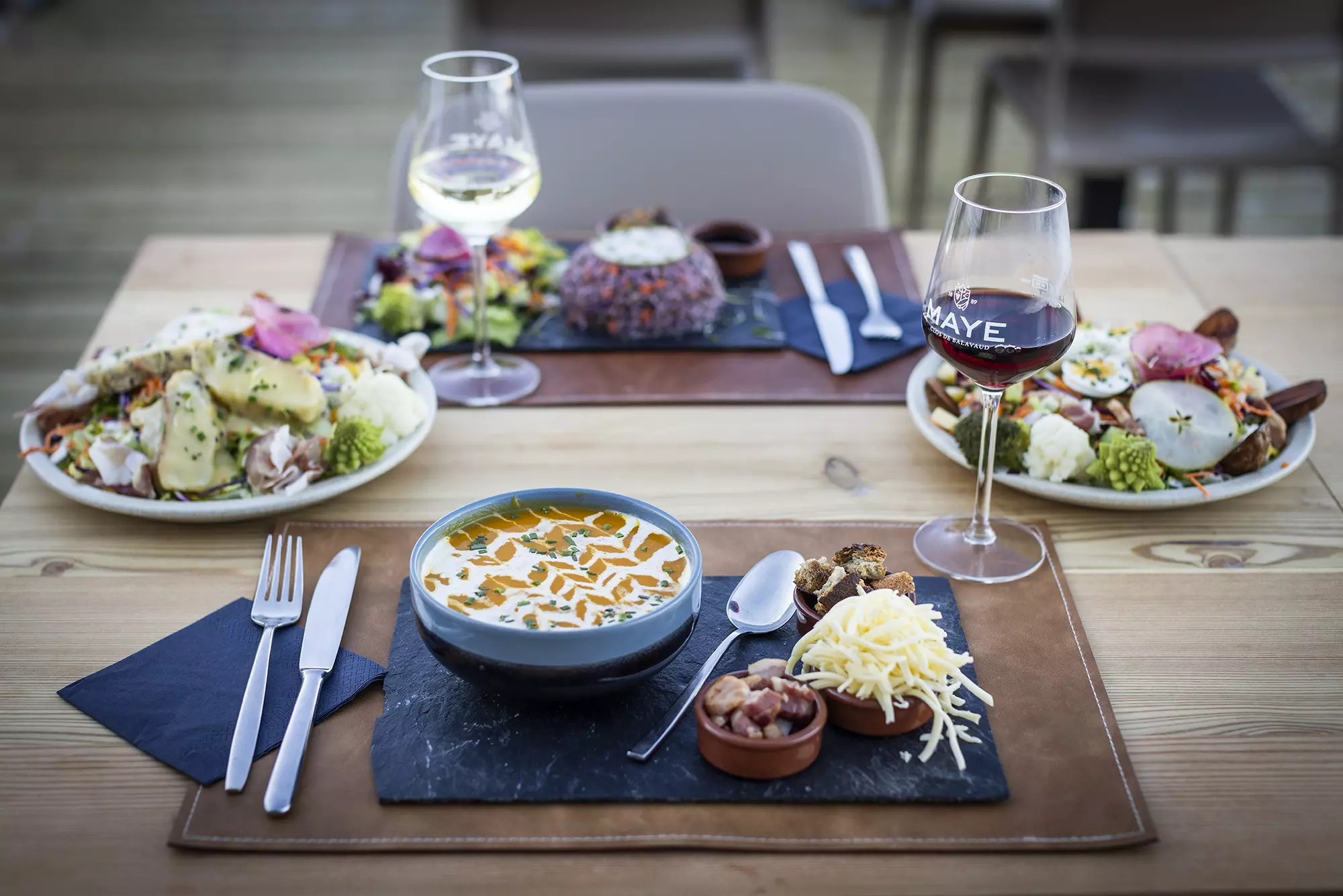 A soup with salads and drinks in a formal place setting