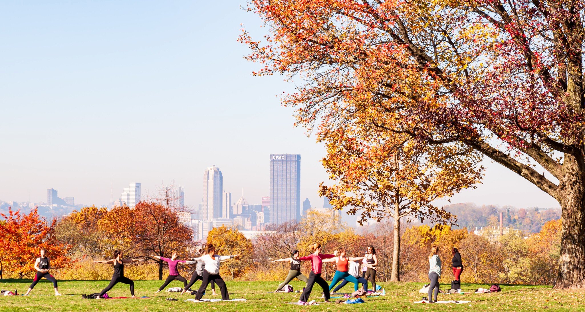 Pittsburgh, Pennsylvania, USA 11/7/20 A group of women having a yoga class in Schenley Park with downtown Pittsburgh in the background on a hazy fall morning