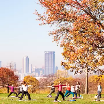Pittsburgh, Pennsylvania, USA 11/7/20 A group of women having a yoga class in Schenley Park with downtown Pittsburgh in the background on a hazy fall morning