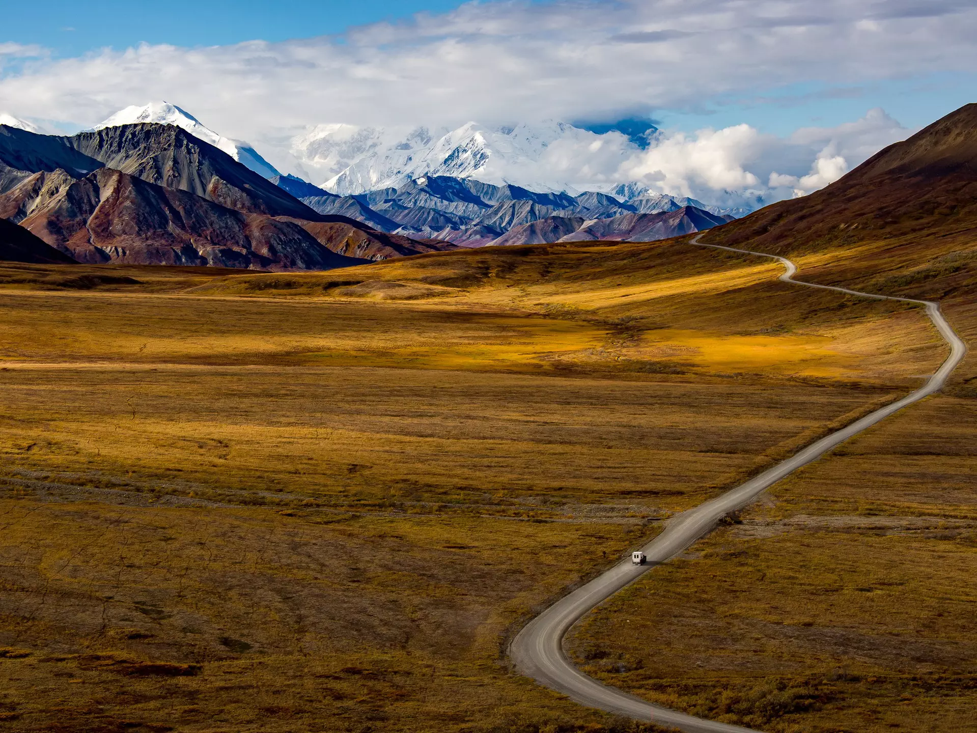 wide angle view of Denali National Park in fall with solitary van on an empty road