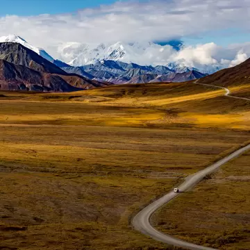 wide angle view of Denali National Park in fall with solitary van on an empty road