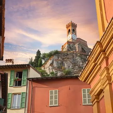 Orange and ochre houses frame the clock tower on a rocky hill above Brisighella in Ravenna province, Italy, at sunset