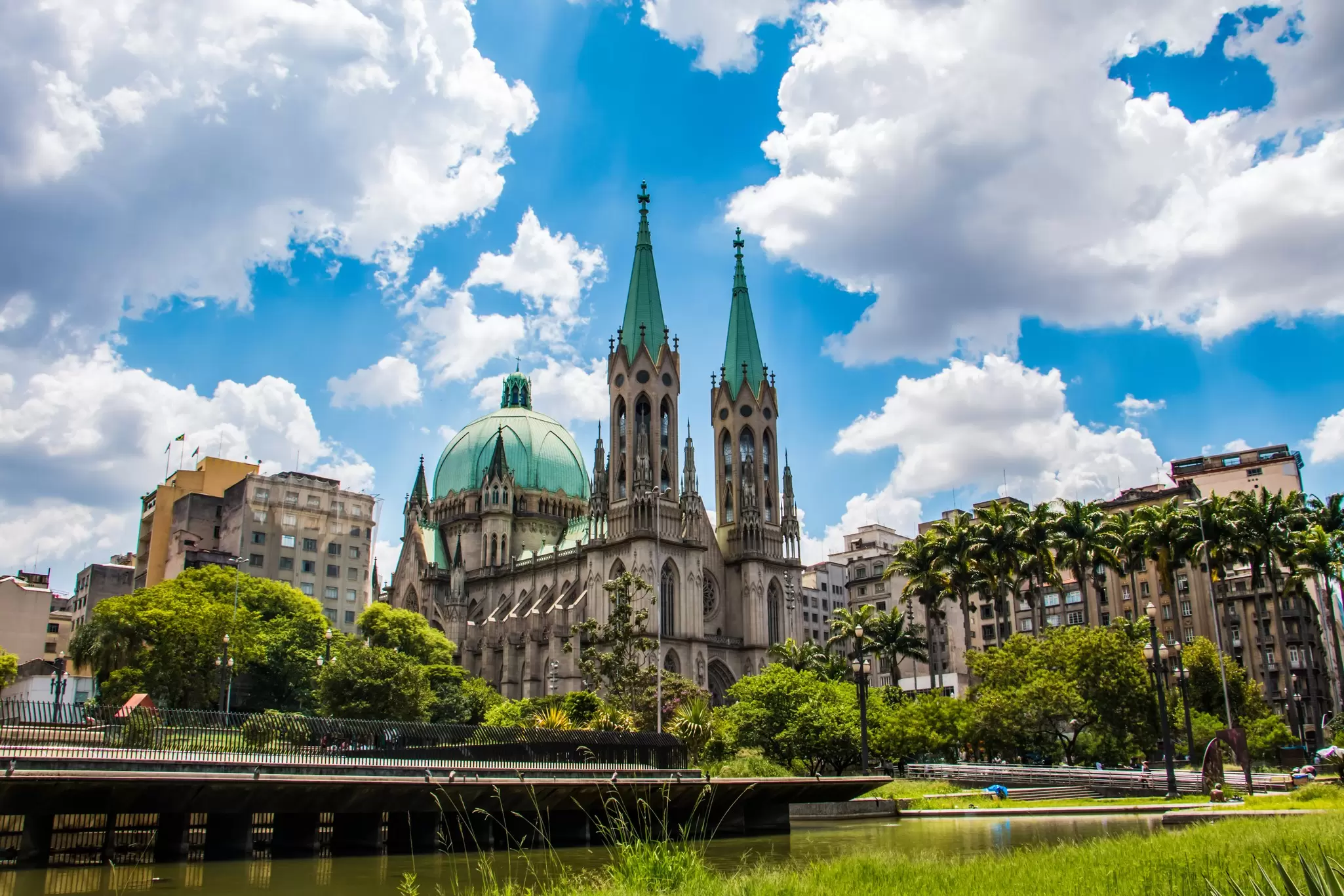 A cathedral with twin spires and a dome at the edge of a green park.