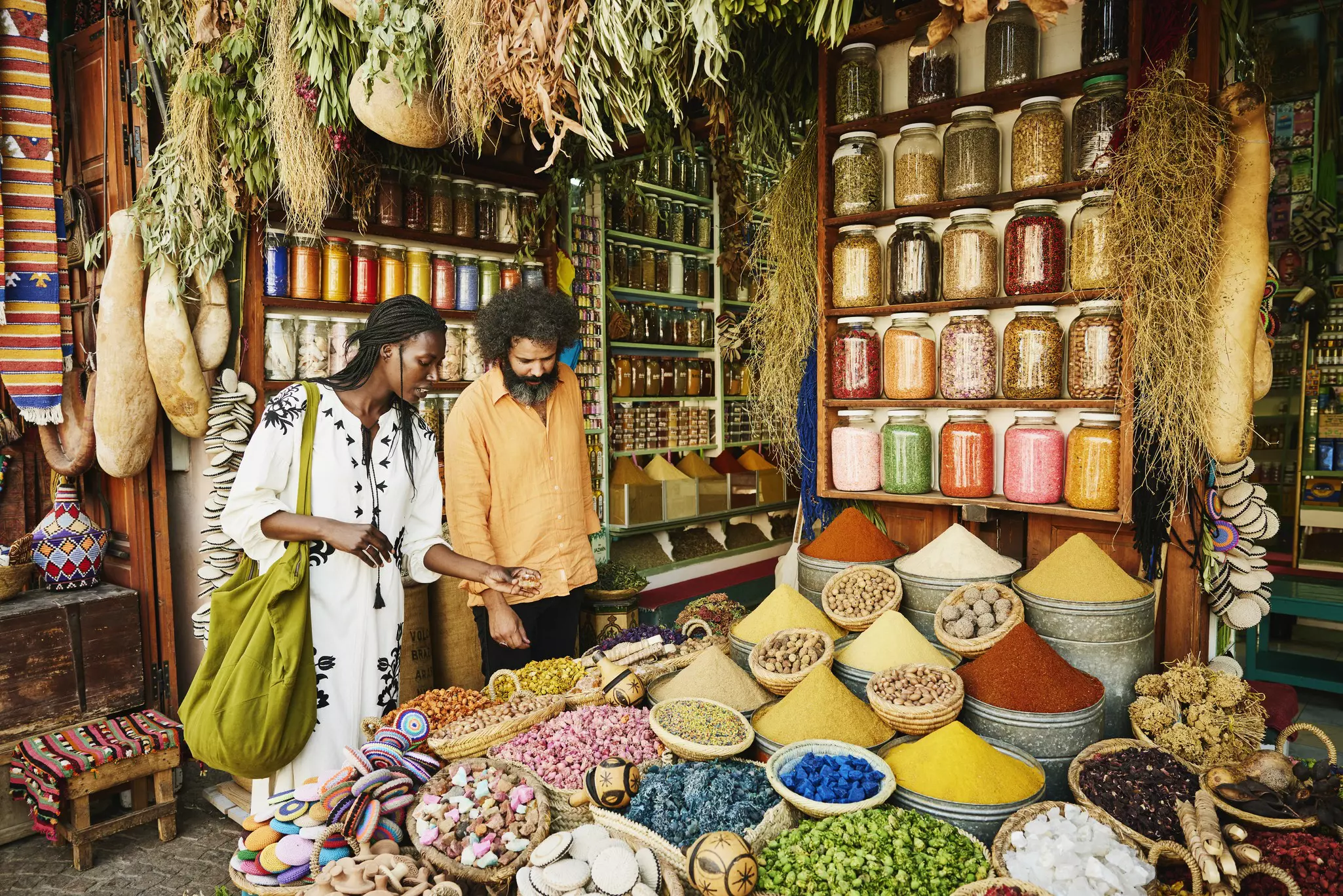 A couple looking at piles of spices at a stand in a souq.
