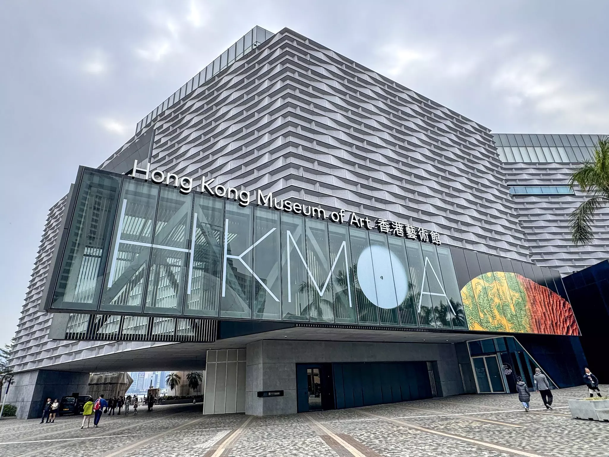 Cobblestone plaze with facade of modern building reading "HKMOA" and "Hong Kong Museum of Art."