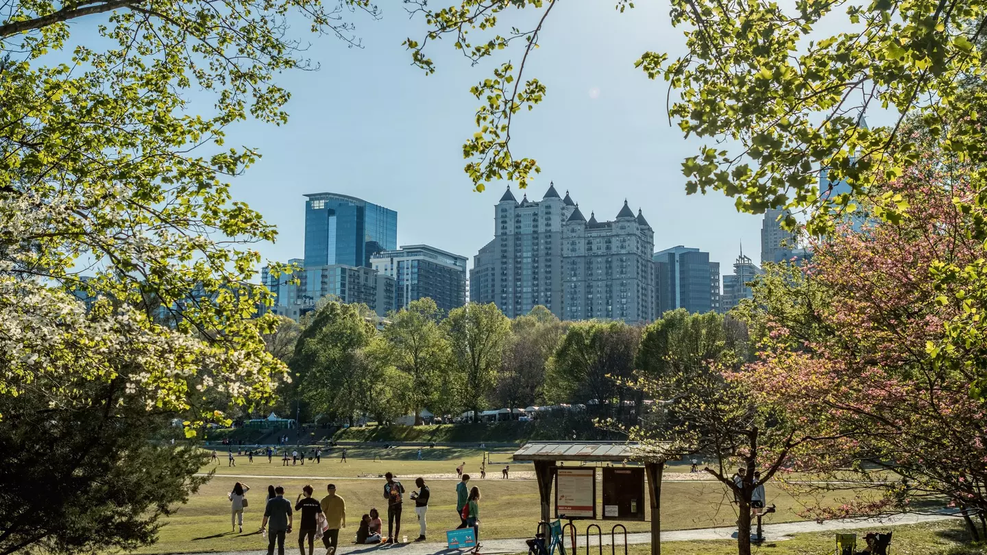 People strolling in Piedmont Park during the Dogwood Festival, with a view of the midtown Atlanta skyline in the background