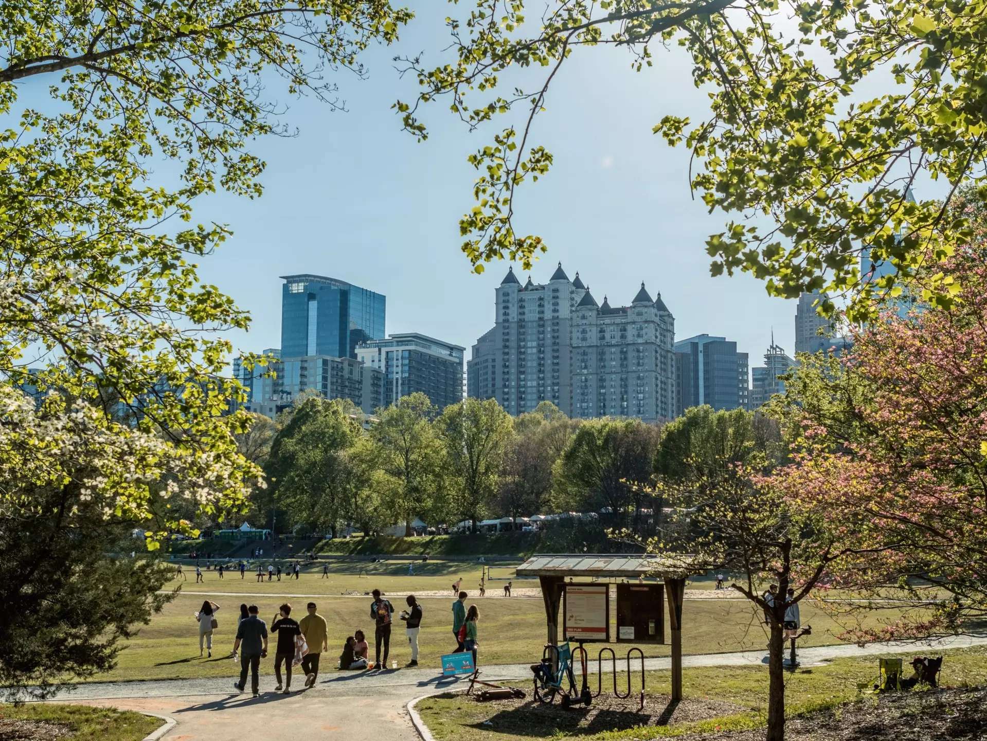 People strolling in Piedmont Park during the Dogwood Festival, with a view of the midtown Atlanta skyline in the background