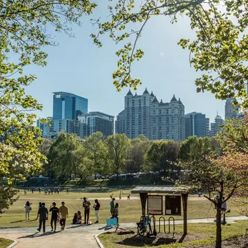 People strolling in Piedmont Park during the Dogwood Festival, with a view of the midtown Atlanta skyline in the background