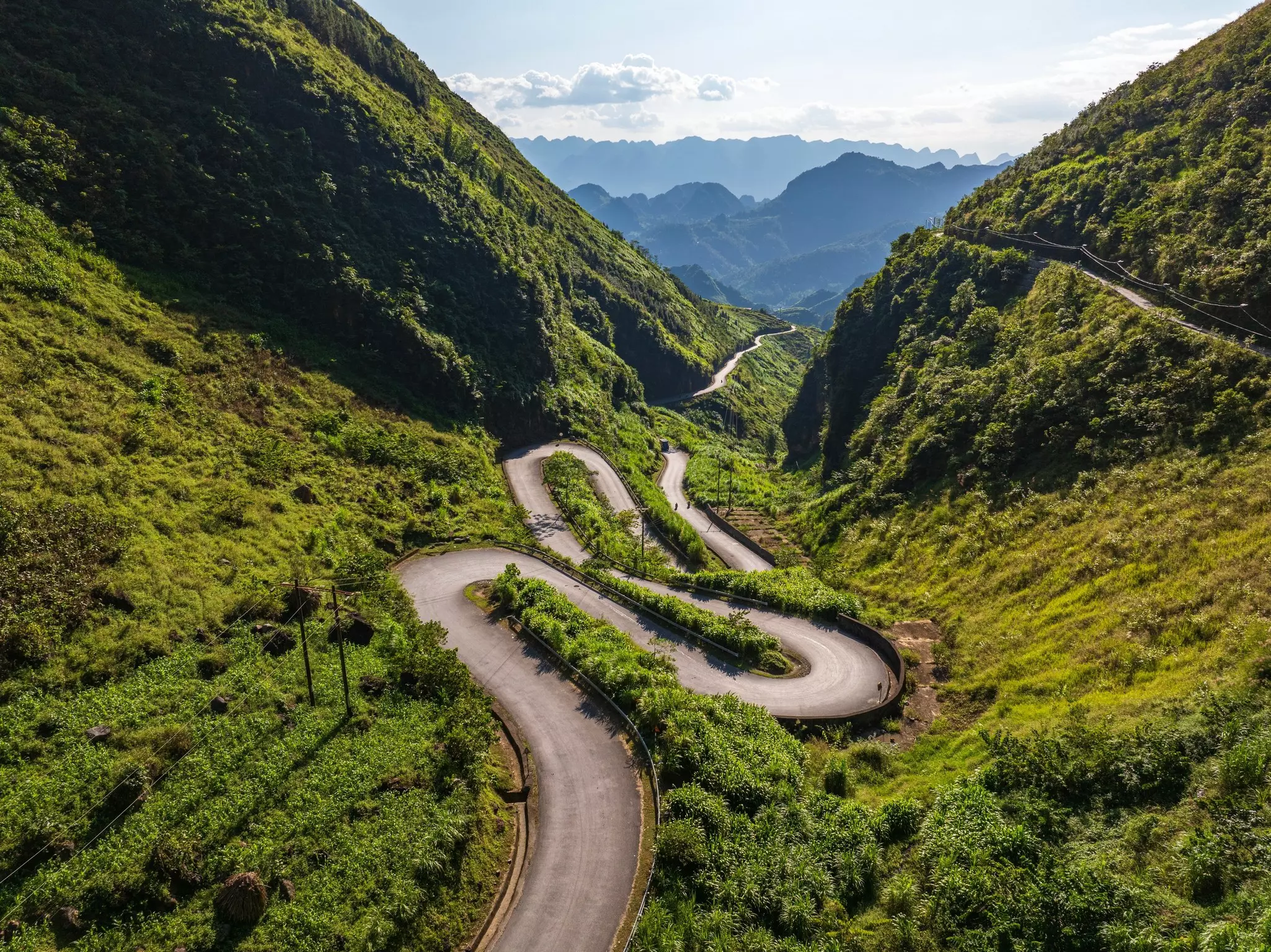 A windy road through a lush green mountain.