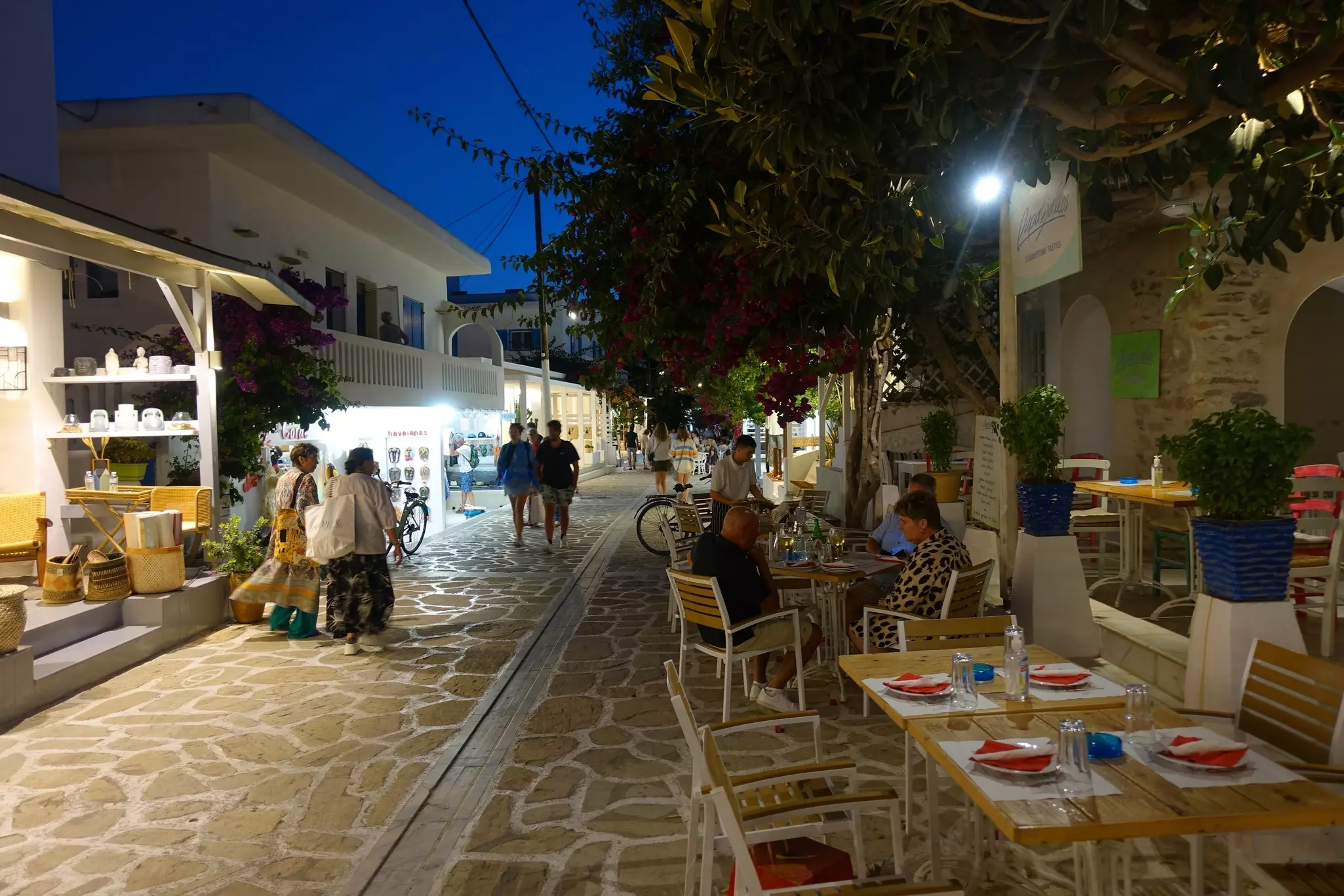 Shops and a tavern with outdoor tables in a plaza at night