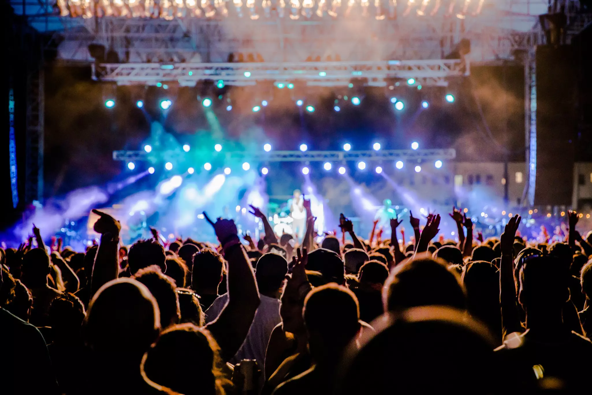A view towards the stage over the heads of festival goers at night